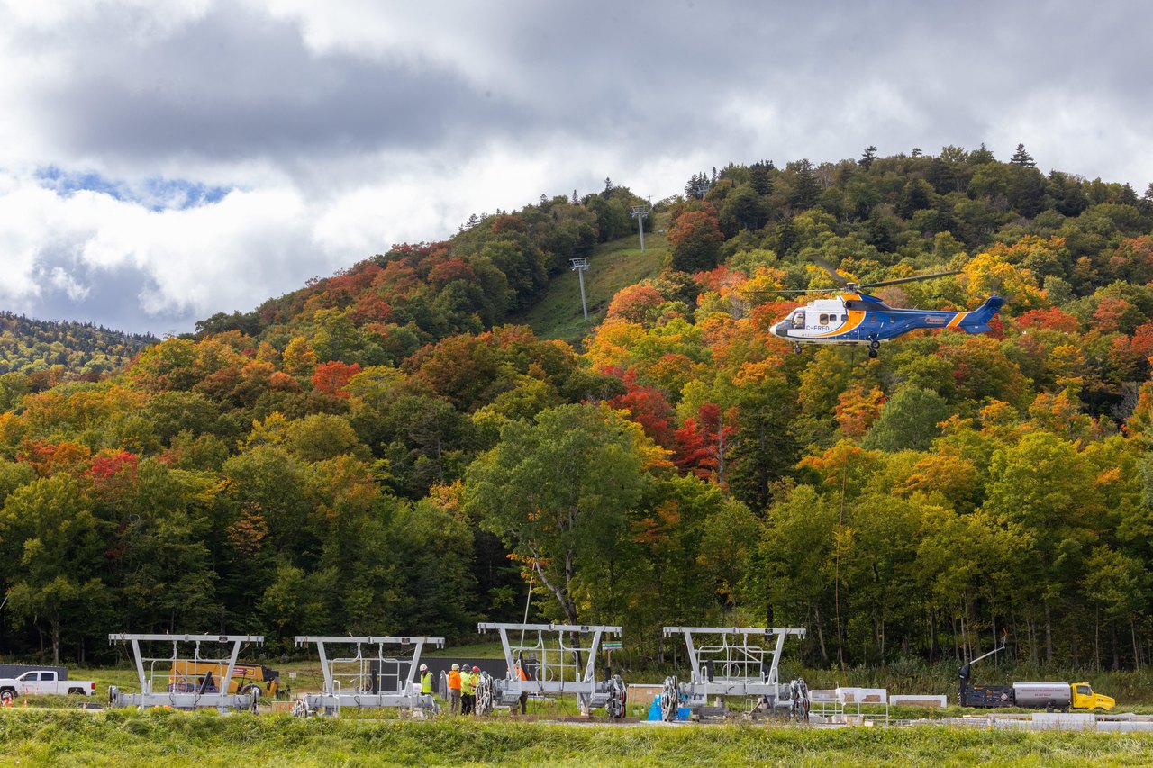 A helicopter works above autumn foliage at Killington’s Snowdon lift construction site.